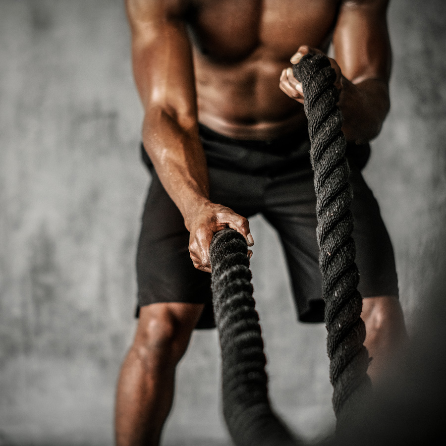 athletic man exercising with weighted ropes